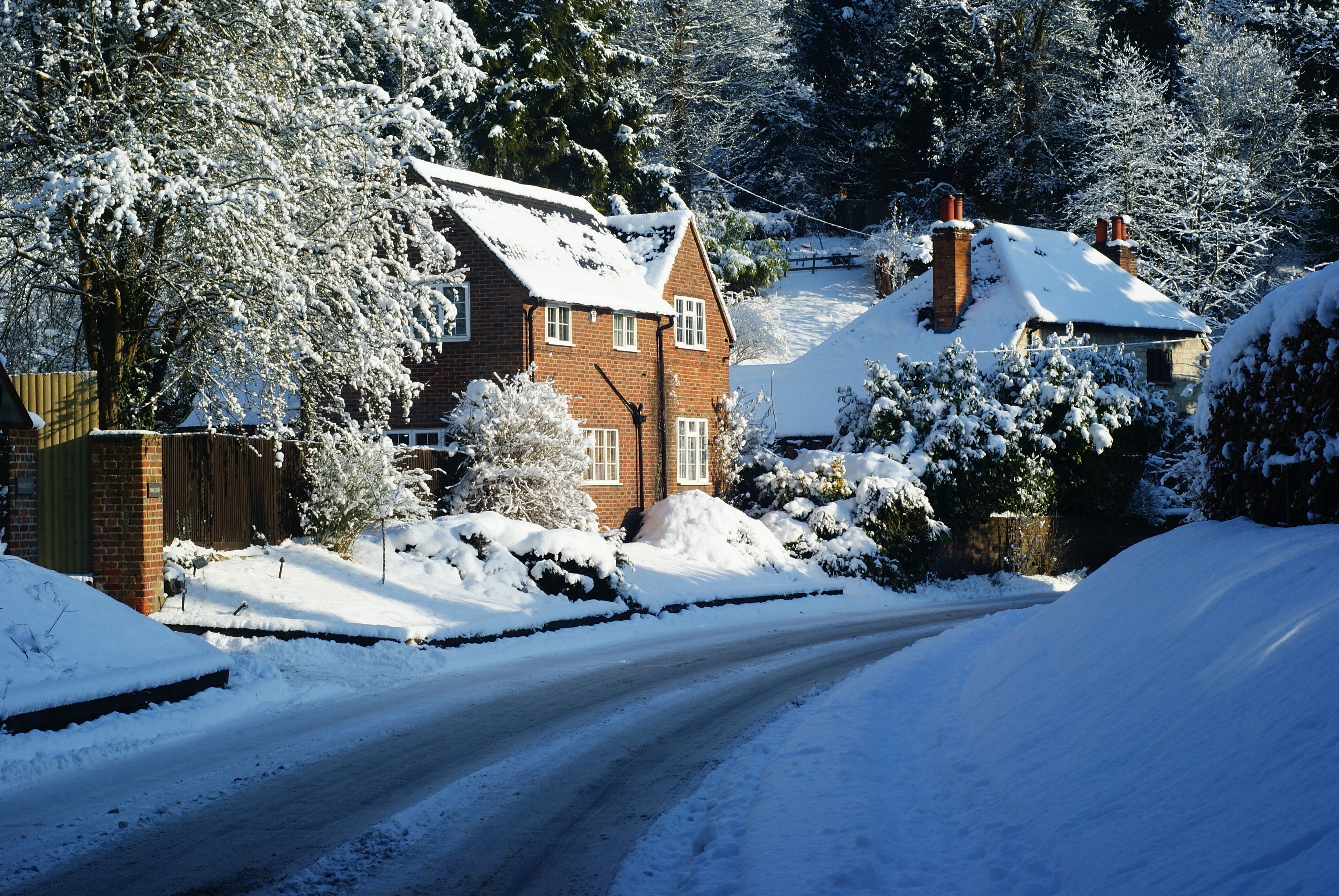 A snow-covered residential area with houses, a road, and trees.