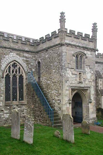 A historic stone building with a staircase, arched windows, and a black door.