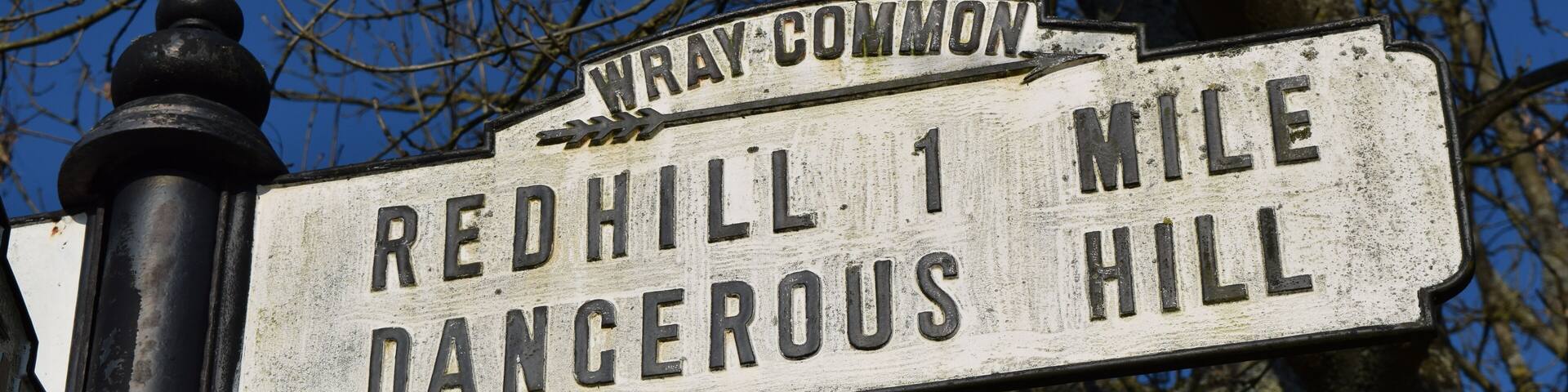 Old british rural signpost warning of dangerous hill