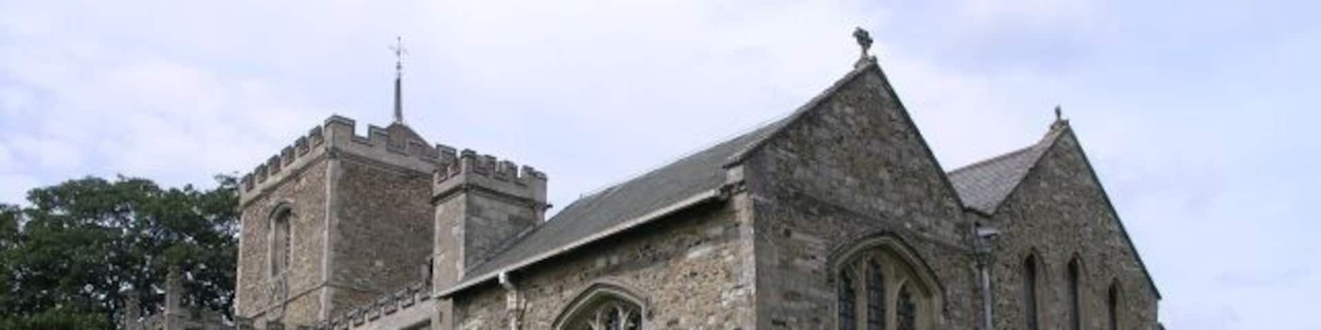 St Mary the Virgin, Bletchingley. The tower dates back to circa 1090, with the porch and oak door dating to 1460. The tower originally had a spire, but this was destroyed when it was struck by lightning in 1606. The nave is comparatively modern, being built in 1856. Just beneath the window covered with glass is a smaller round hole (partially covered by a gravestone in this picture). This was possibly used by Roger the Hermit, who is said to have visited these parts in the 13th-century.
