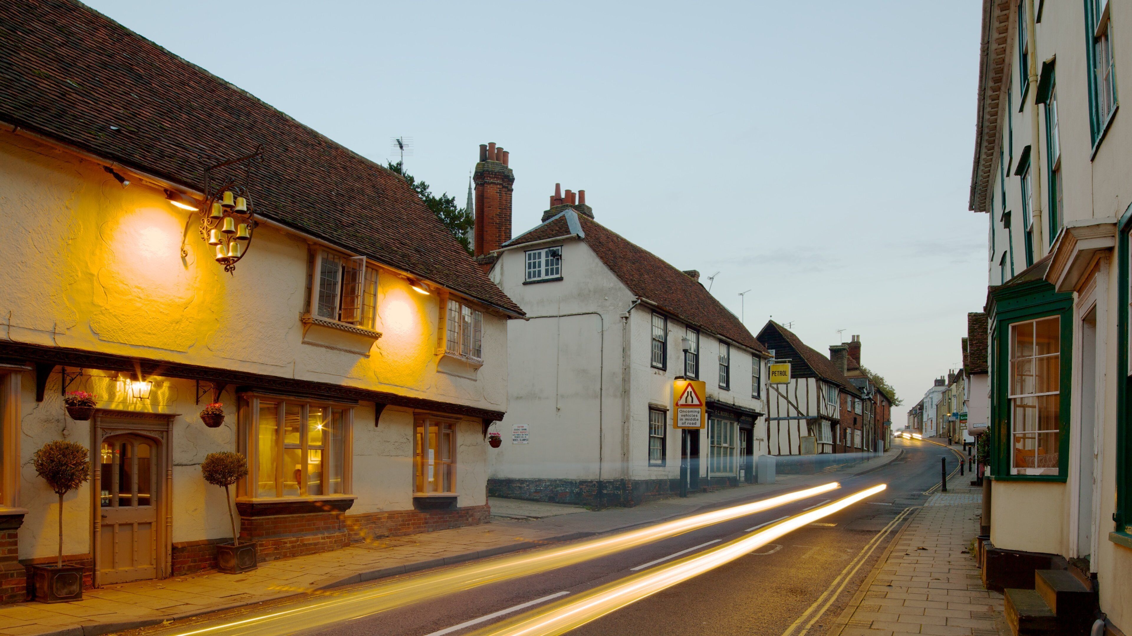 A street lined with traditional buildings, a petrol station sign, and a warning sign.