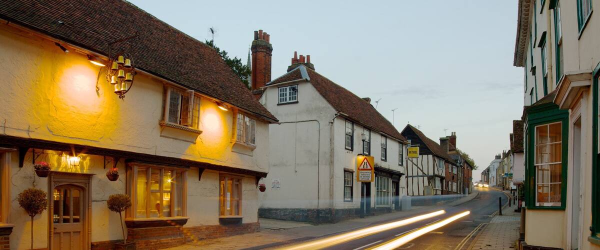 A street lined with traditional buildings, a petrol station sign, and a warning sign.