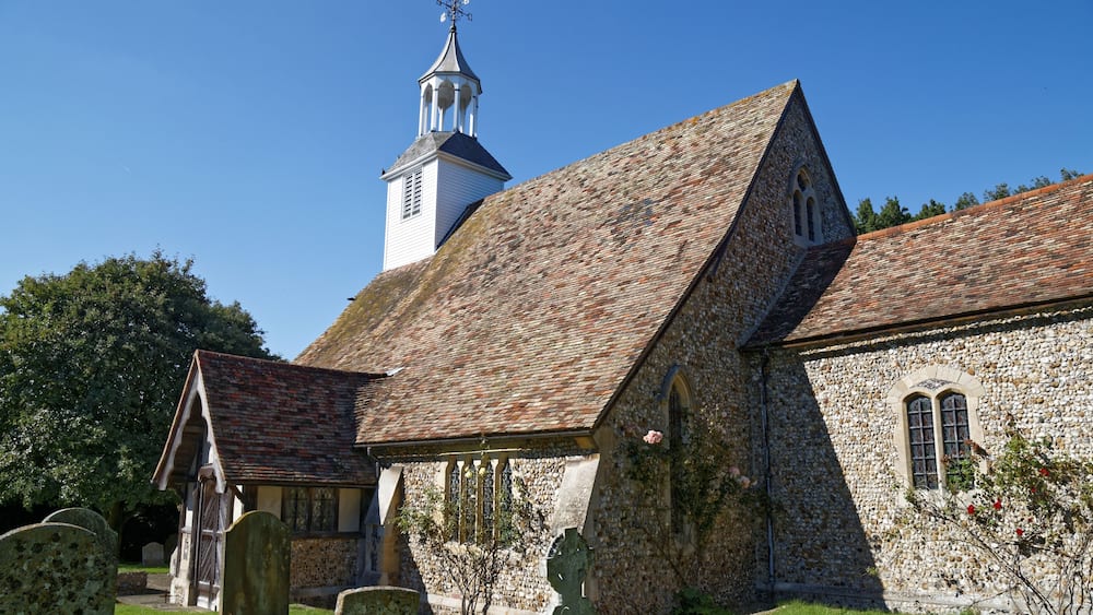 Une église avec une façade en pierre, un clocher et un cimetière.