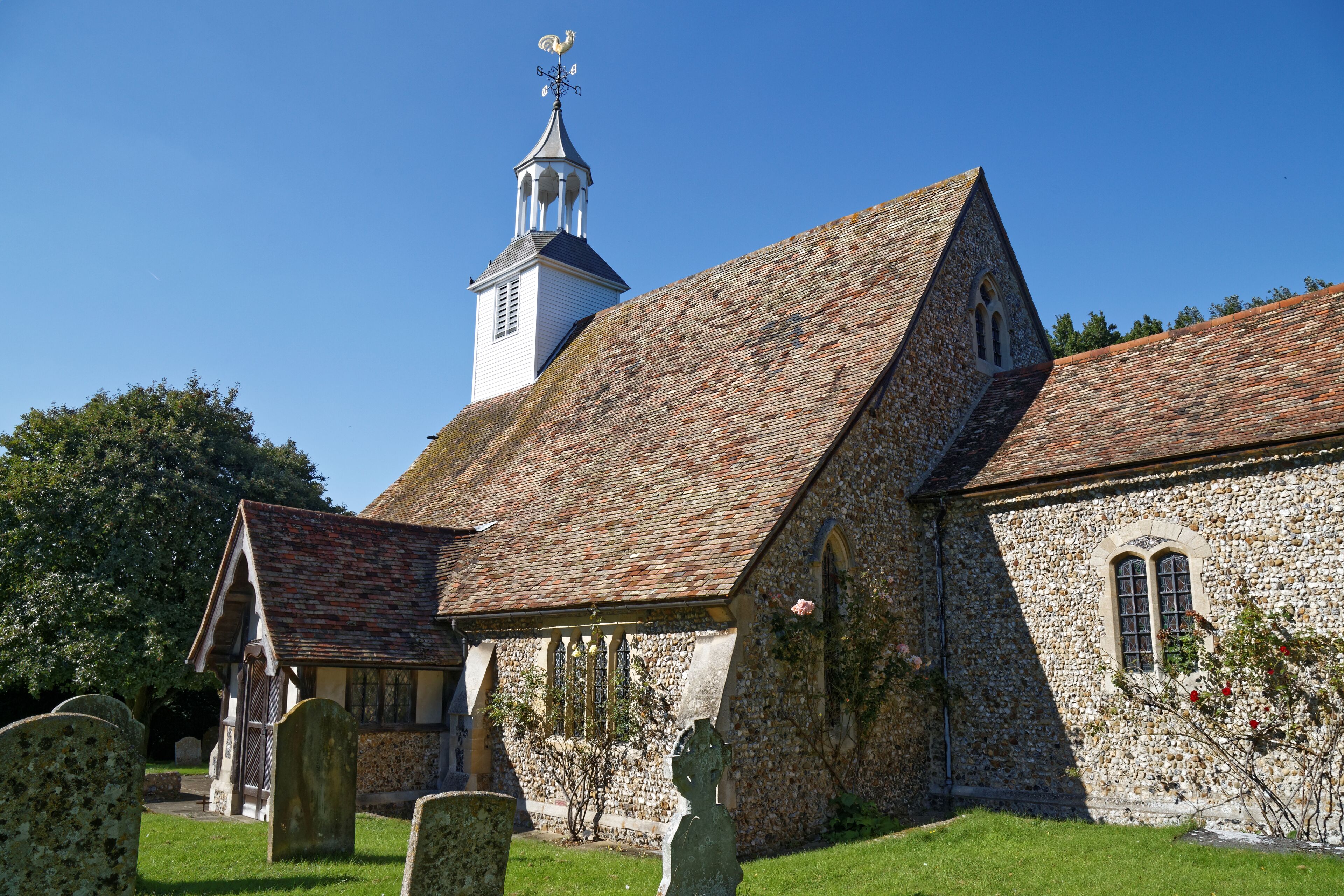 A church with a stone facade, a bell tower, and a graveyard.