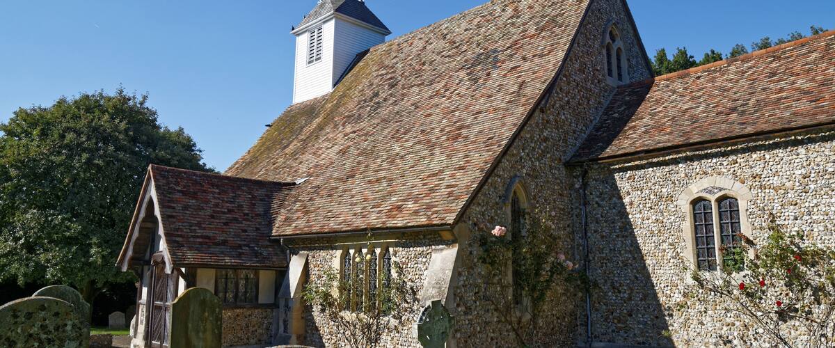 A church with a stone facade, a bell tower, and a graveyard.
