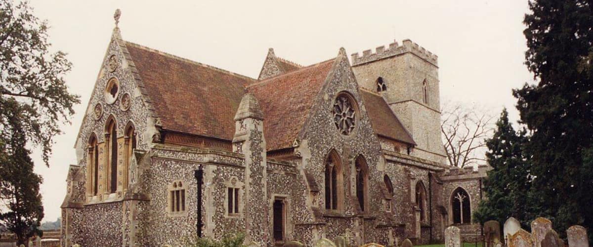 A historic church with a stone facade and pointed arches, surrounded by a cemetery with numerous gravestones.
