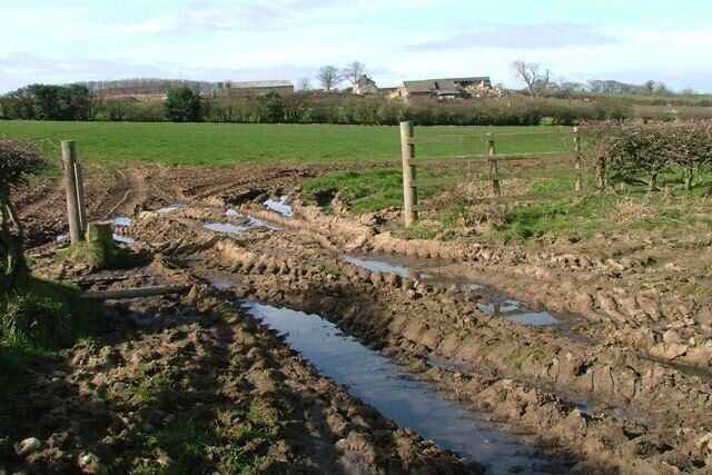 Muddy Field Entrance With Blue House Farm in the distance.