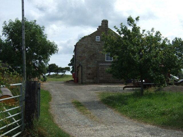 A rural stone building with a gravel path leading to it.