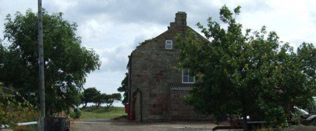 A rural stone building with a gravel path leading to it.