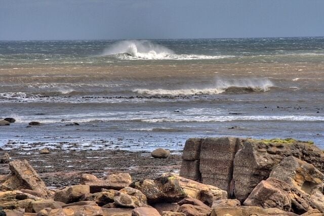 Low Tide at Port Mulgrave View offshore from the relative shelter of the old harbour. The south westerly wind is blowing back the waves as they break over the scar.