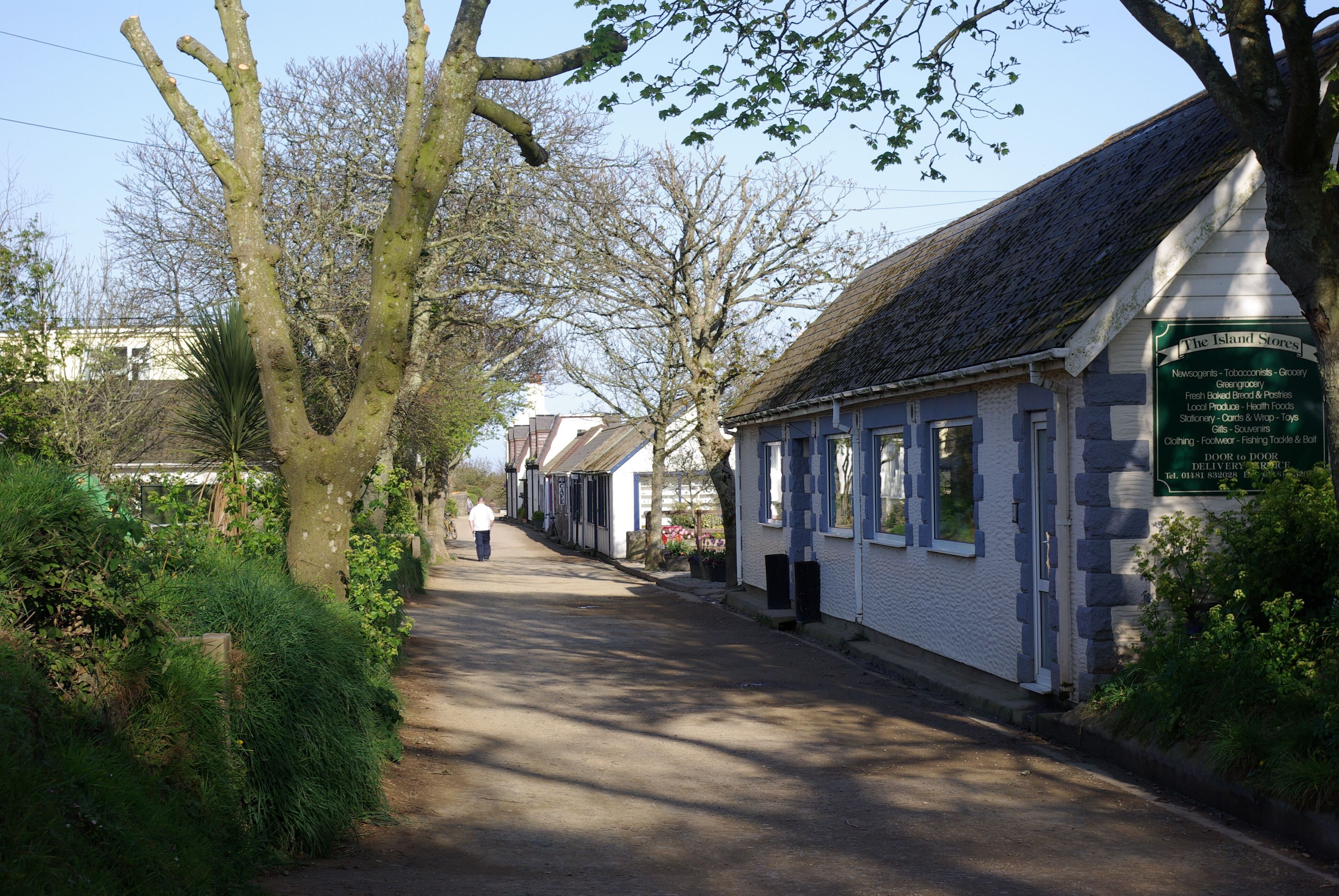 Sark eine der Kanalinsel. Die Straße mit den Geschäften und der Post. Der Blick geht in Richtung der Haltestelle des Treckers für die Personenbeföferung (geotag in den EXIF-Daten).