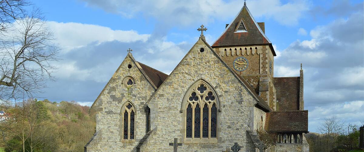 A stone church with a tall steeple and a clock.