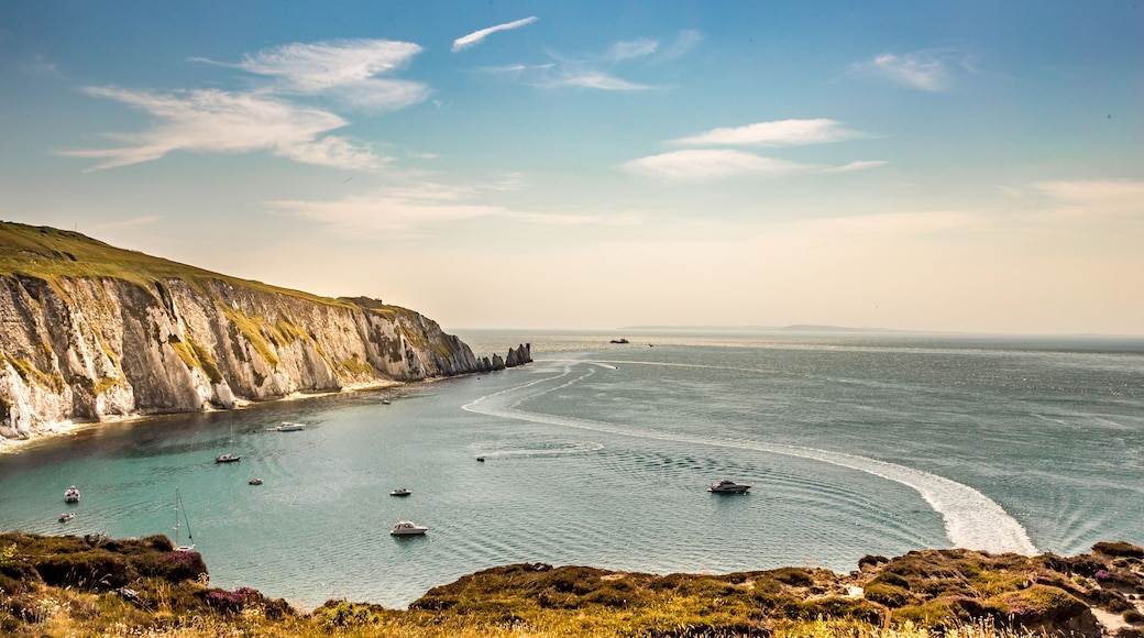 Un paysage côtier avec des falaises, une mer calme et des bateaux.