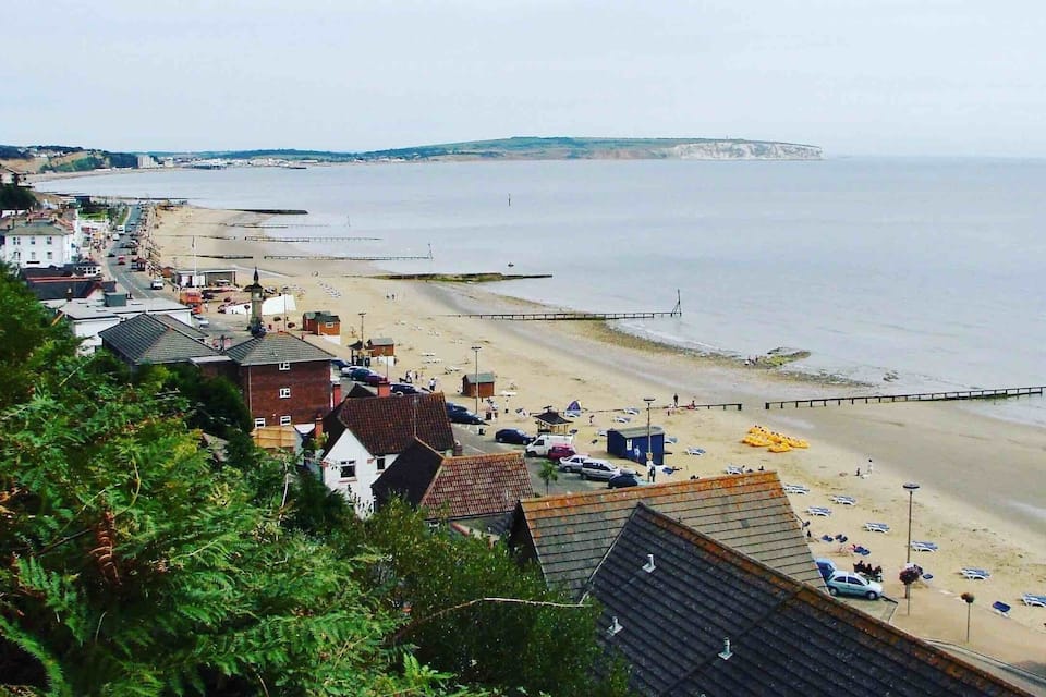 Een kustplaatsje met een strand, huizen en een klif met uitzicht op de zee.