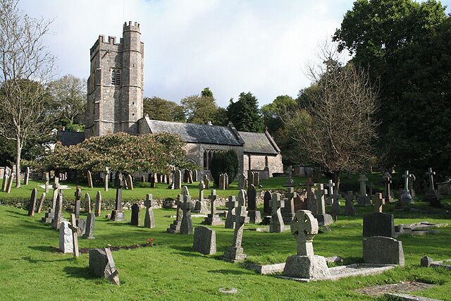A church with a tall tower, surrounded by a cemetery with numerous gravestones.