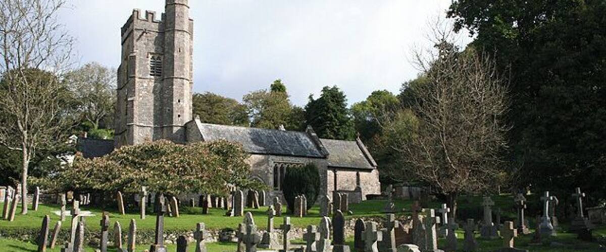 A church with a tall tower, surrounded by a cemetery with numerous gravestones.