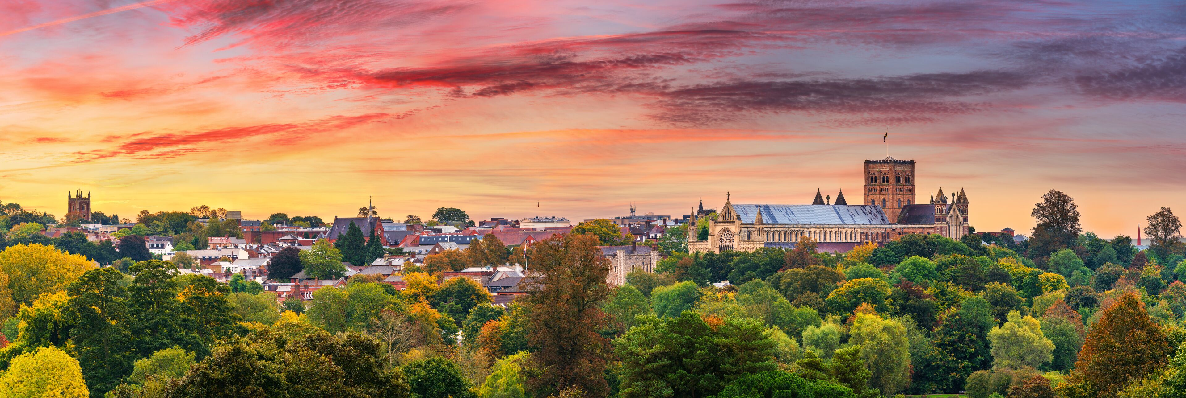 A cityscape with a prominent cathedral and tower during sunset.