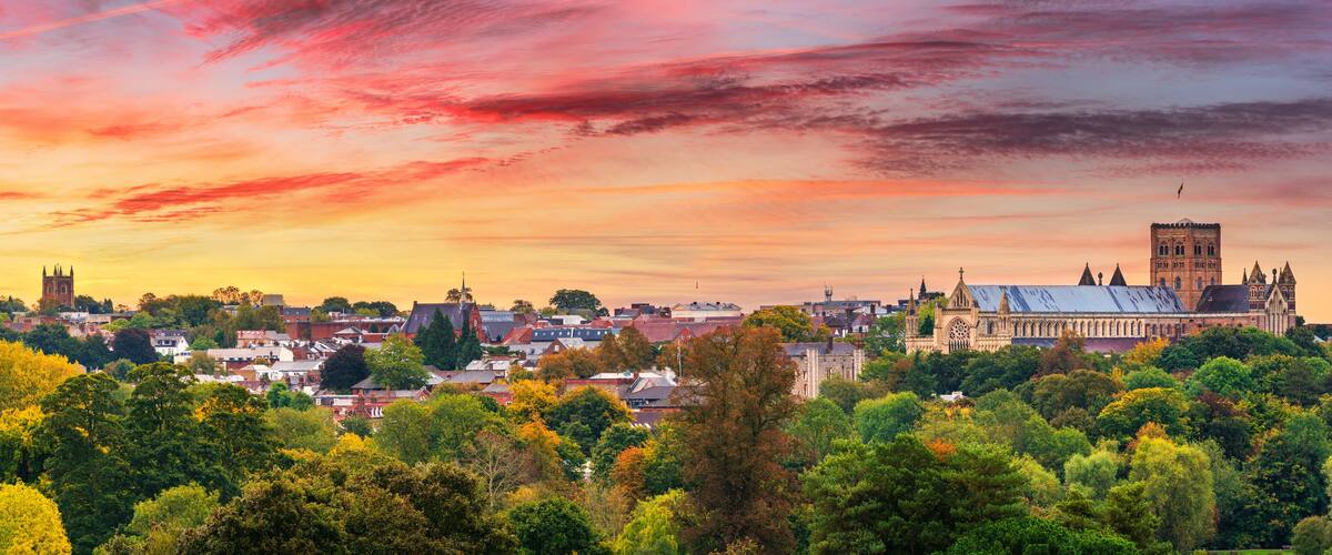 A cityscape with a prominent cathedral and tower during sunset.