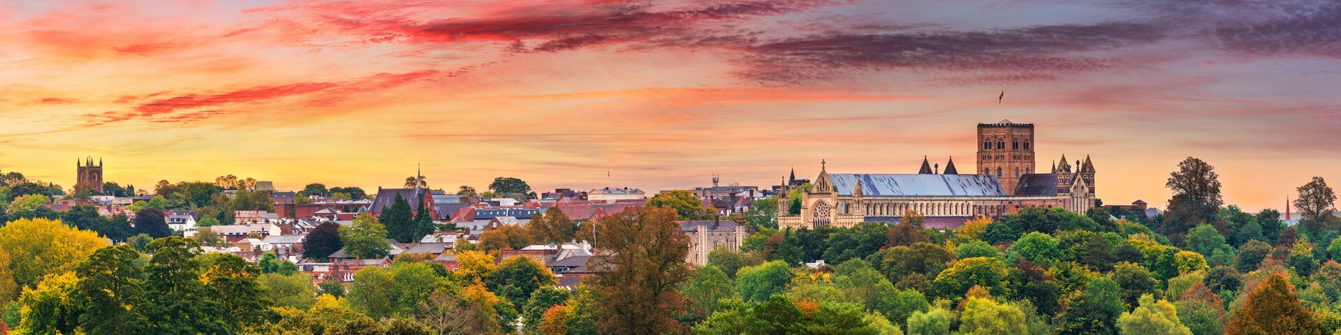 A cityscape with a prominent cathedral and tower during sunset.