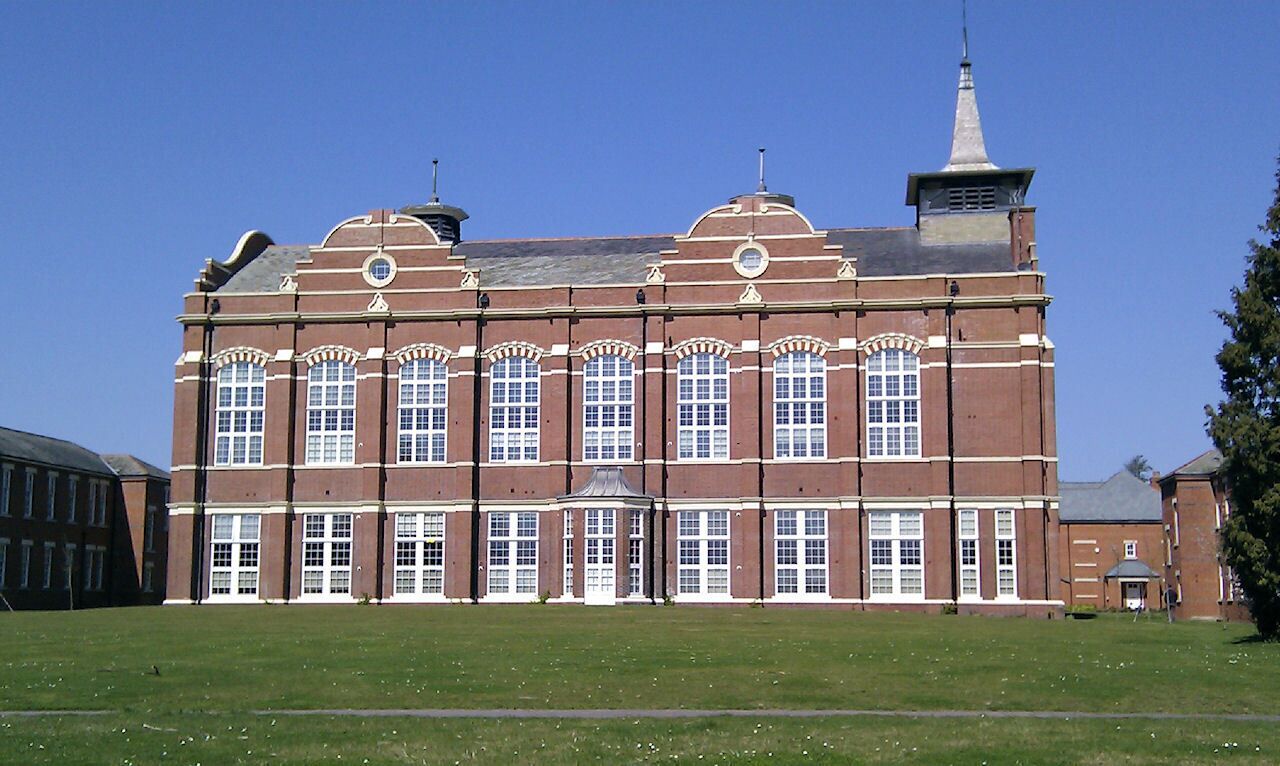 A large red brick building with arched windows and a tower.