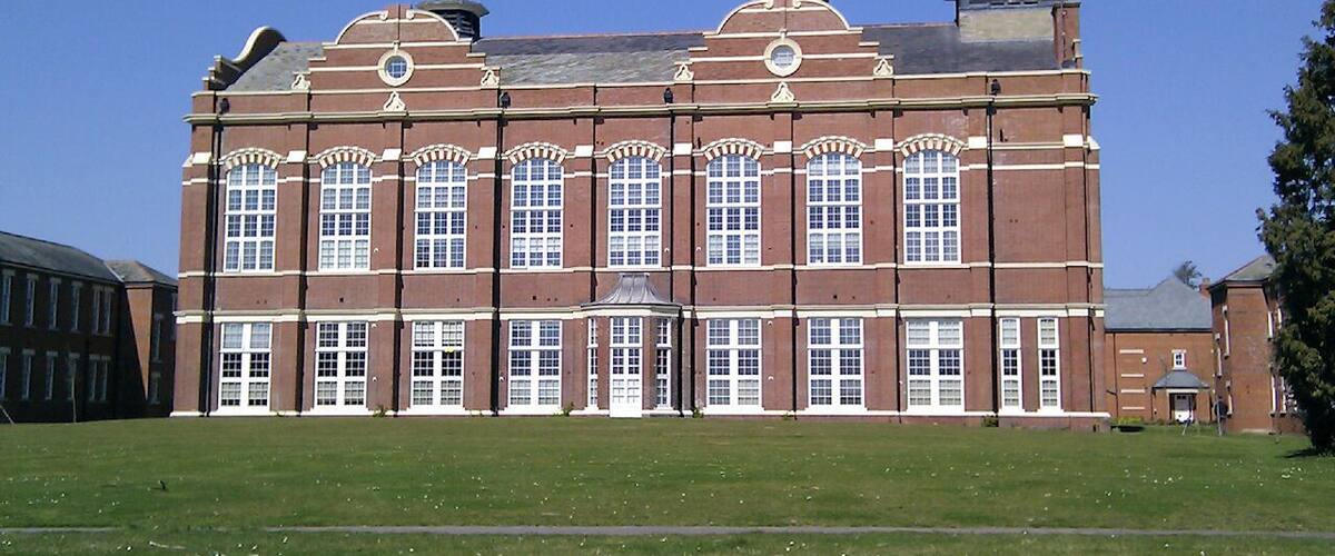 A large red brick building with arched windows and a tower.