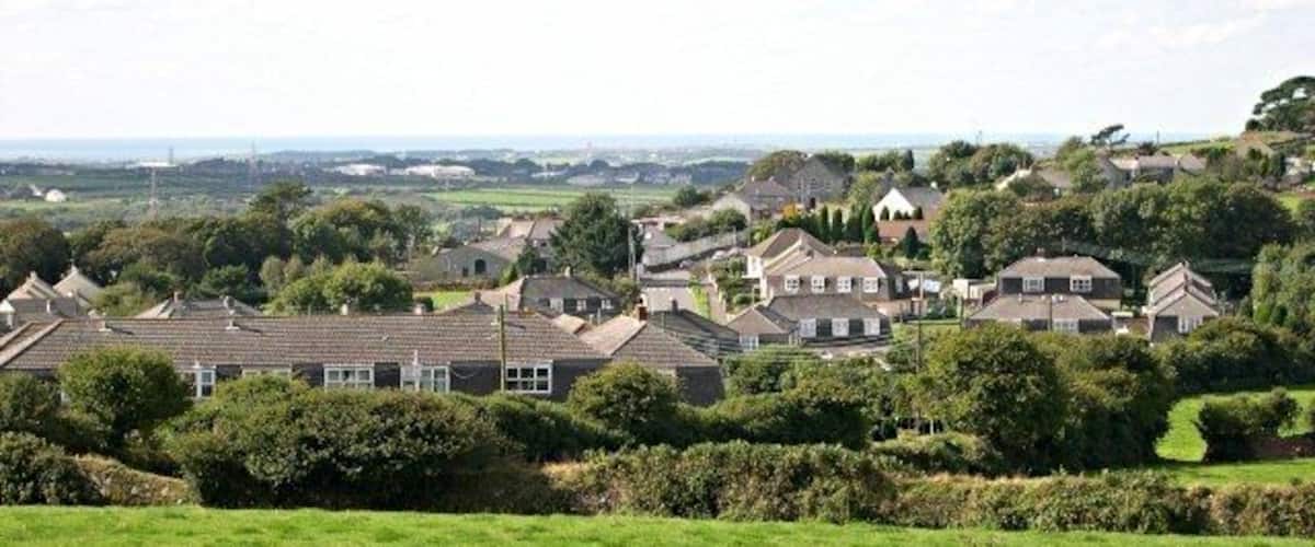 A rural village with houses, green fields, and trees.