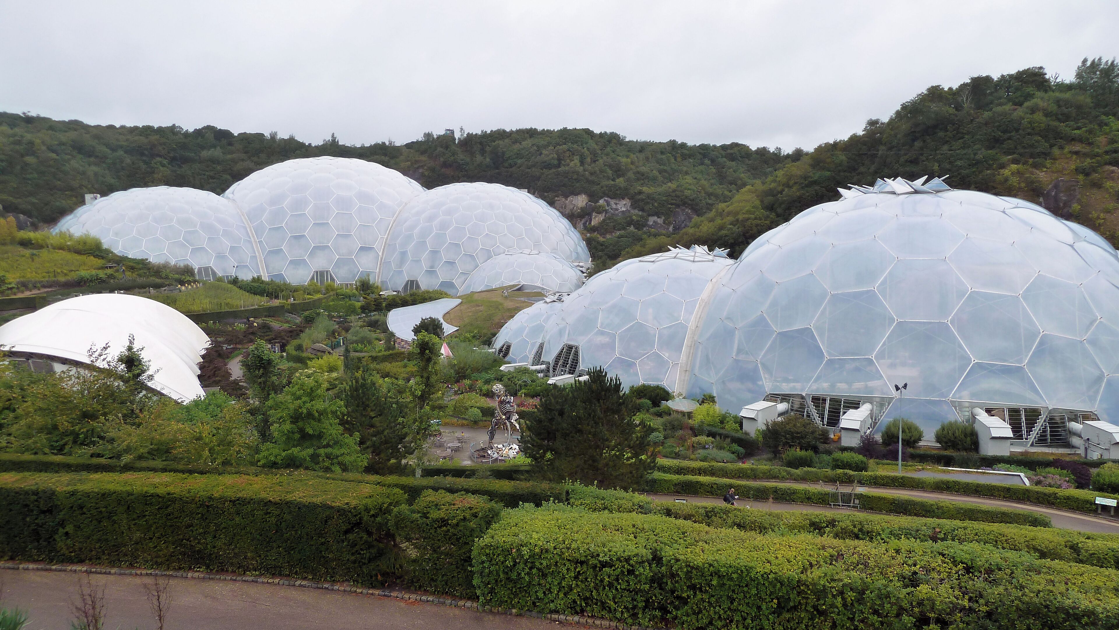 A series of large, dome-shaped structures with a honeycomb pattern, surrounded by lush greenery and hills.