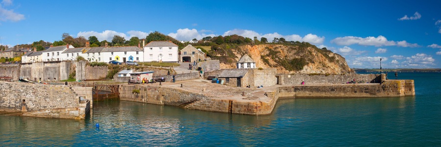 A coastal town with stone buildings, a harbor, and a cliff.