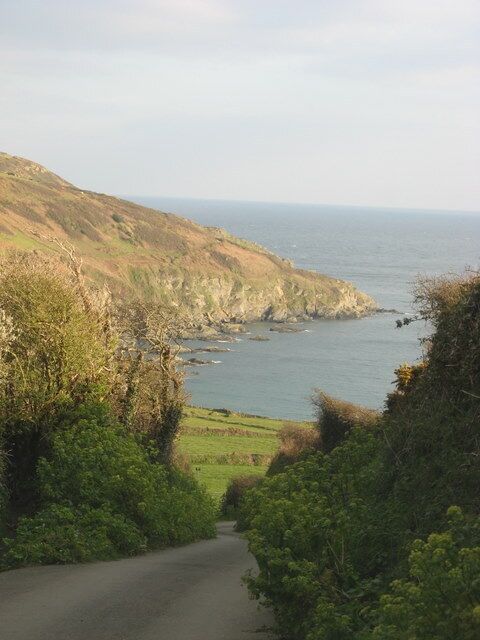 A coastal road with a view of the sea and hills.