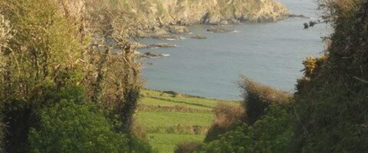 A coastal road with a view of the sea and hills.