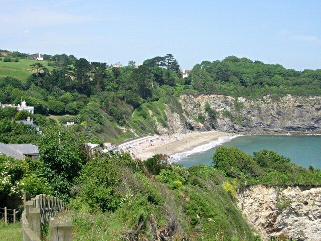 A coastal landscape with a beach, cliffs, and greenery.