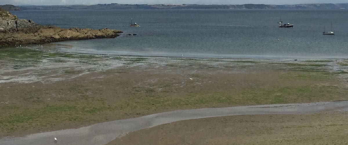 A coastal landscape with rocky shores, a sandy beach, and calm sea.