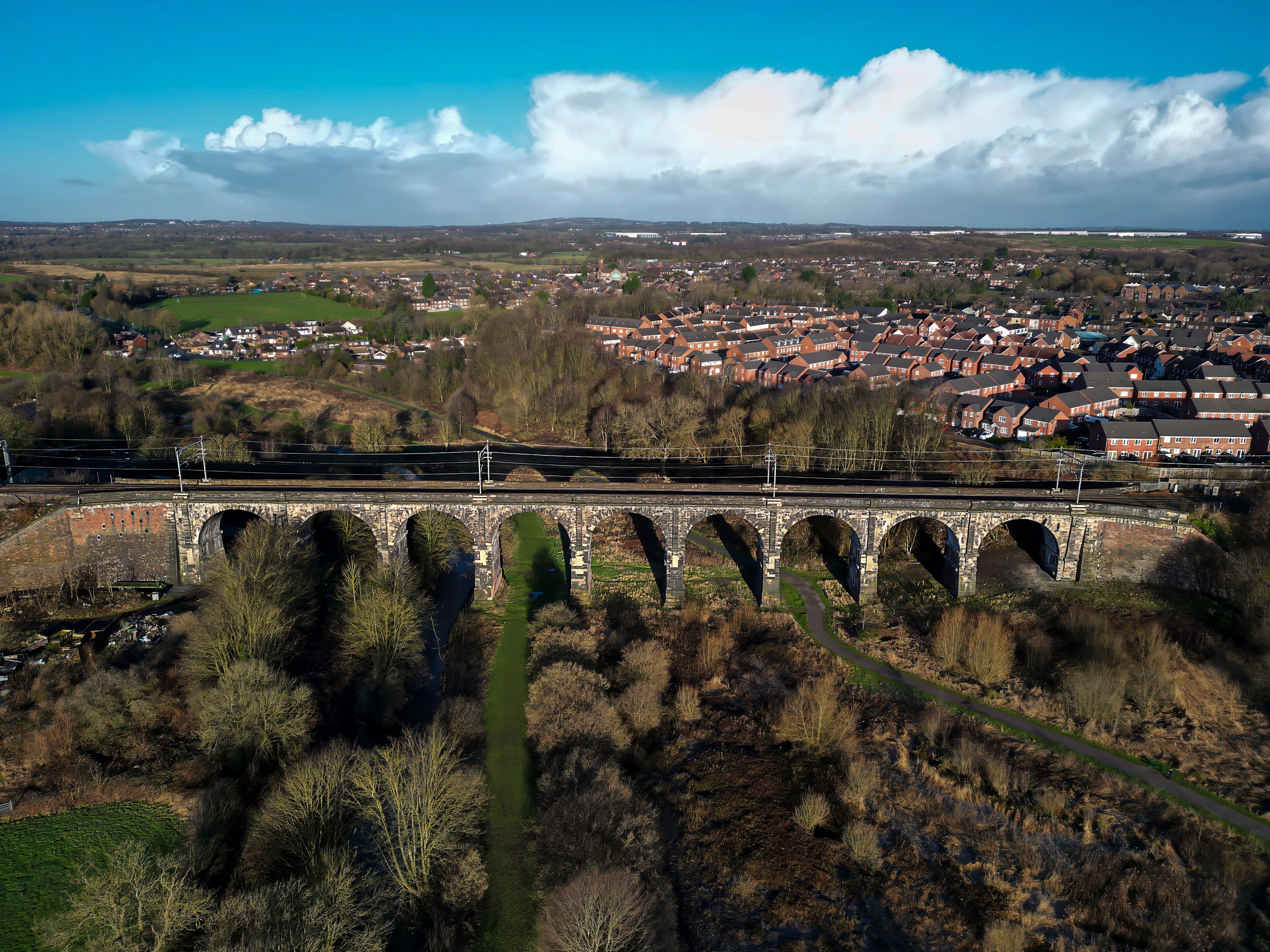 A railway bridge over a river, a town in the background, and surrounding hills.