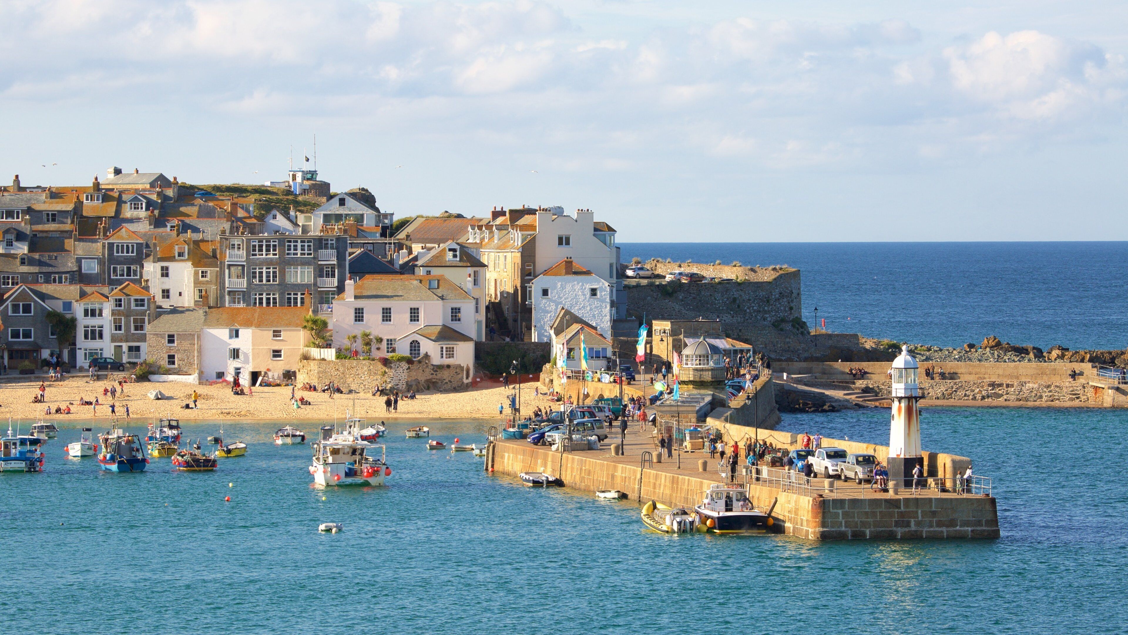 A coastal town with a lighthouse, boats, and historic buildings.