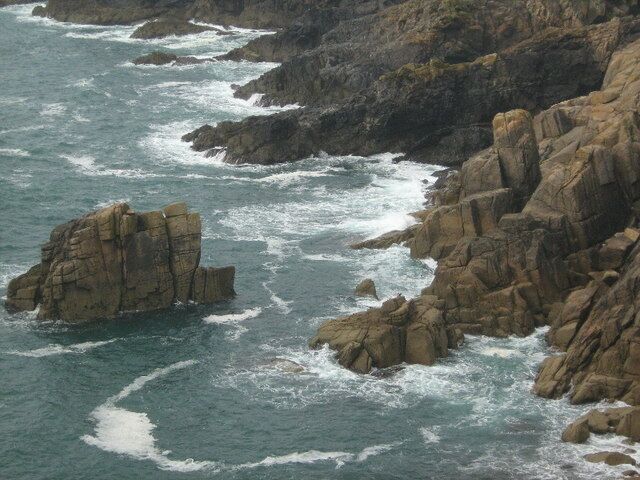 Una costa rocosa con olas rompiendo contra las rocas.