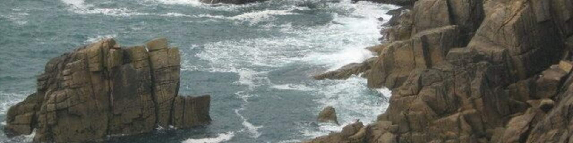 Una costa rocosa con olas rompiendo contra las rocas.