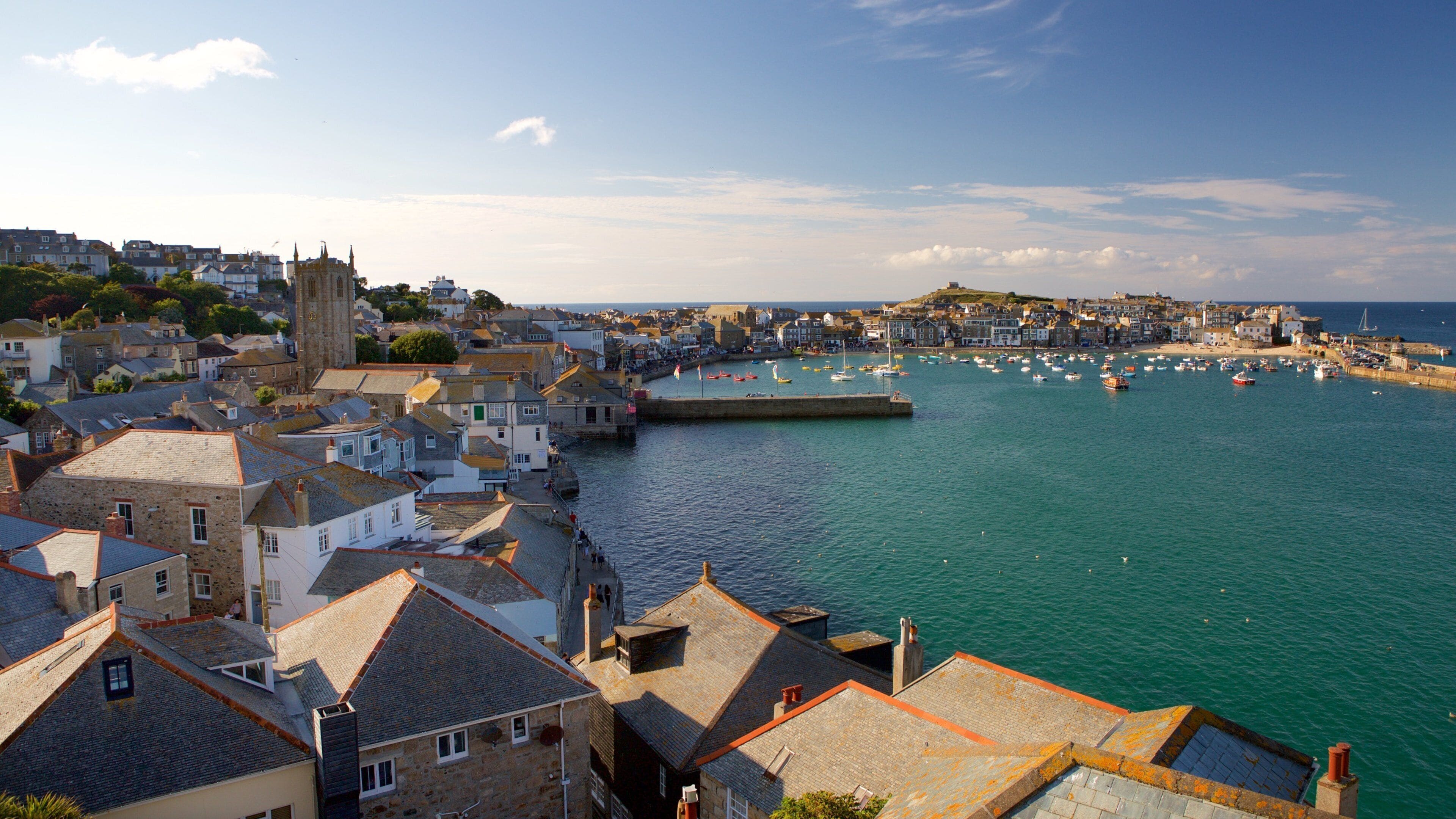 A coastal town with historic buildings, a harbor with boats, and a prominent church.