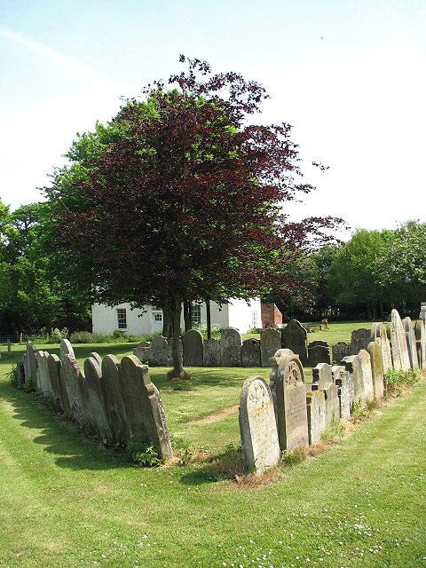 A chapel once stood here. Triangular arrangement of 19th century headstones, standing back to back; the building obscured by the tree growing in the centre is > 798399.