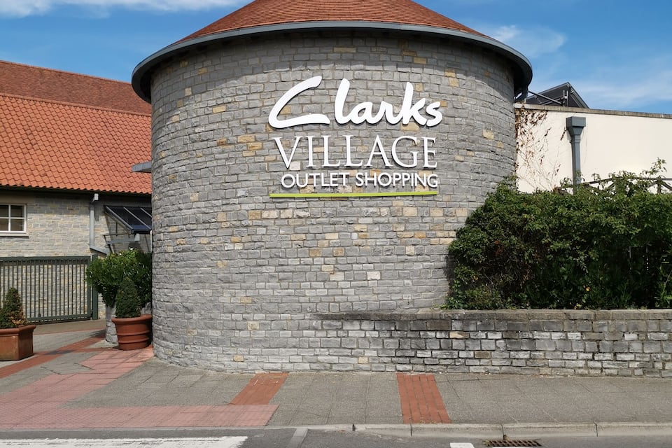 Un edificio de piedra con un letrero que dice "Clarks Village Outlet Shopping".