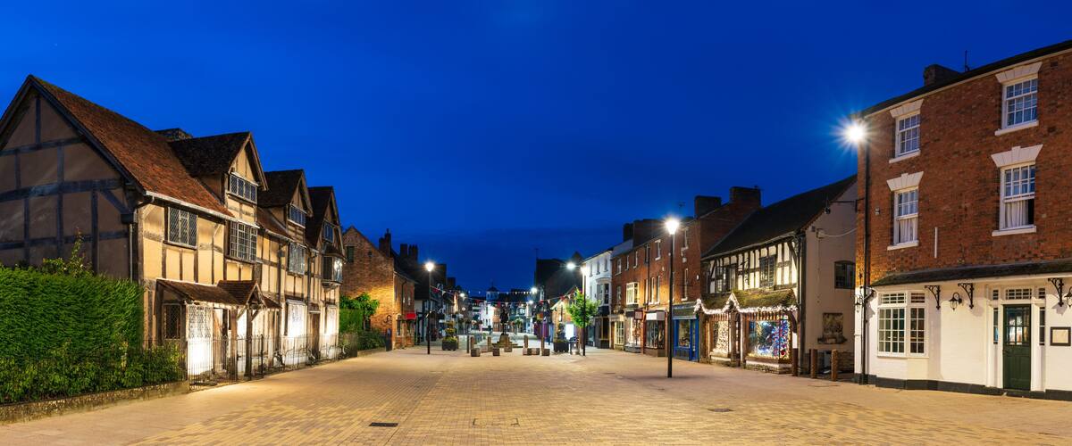 A cobblestone street lined with historic half-timbered houses and a pub.