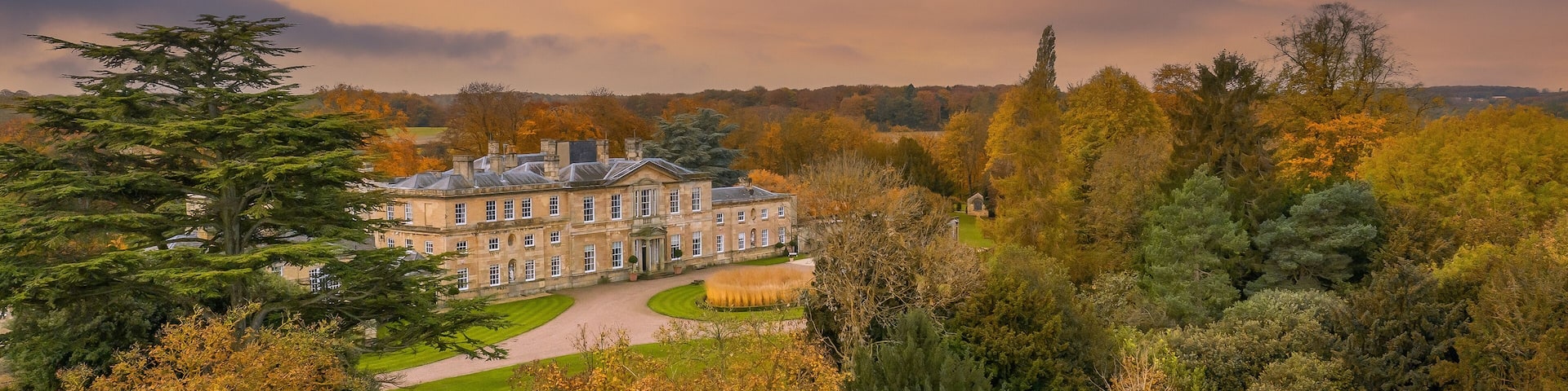 Bowcliffe Hall Yorkshire stately home, wedding venue and offices close to the A1, York, Leeds and Bramham Park. Drone photo showing the front of the main building and trees on an autumn day at sunset