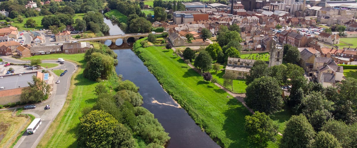 A river flowing through a town with historic buildings and a bridge.