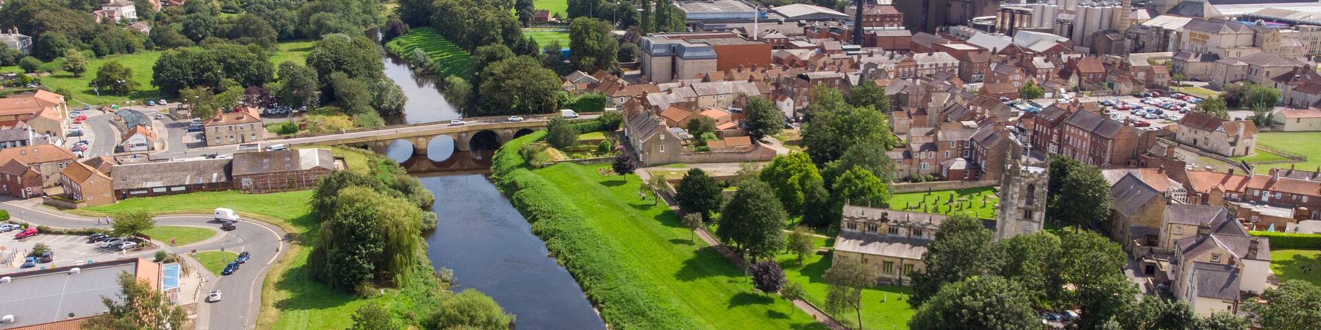 A river flowing through a town with historic buildings and a bridge.