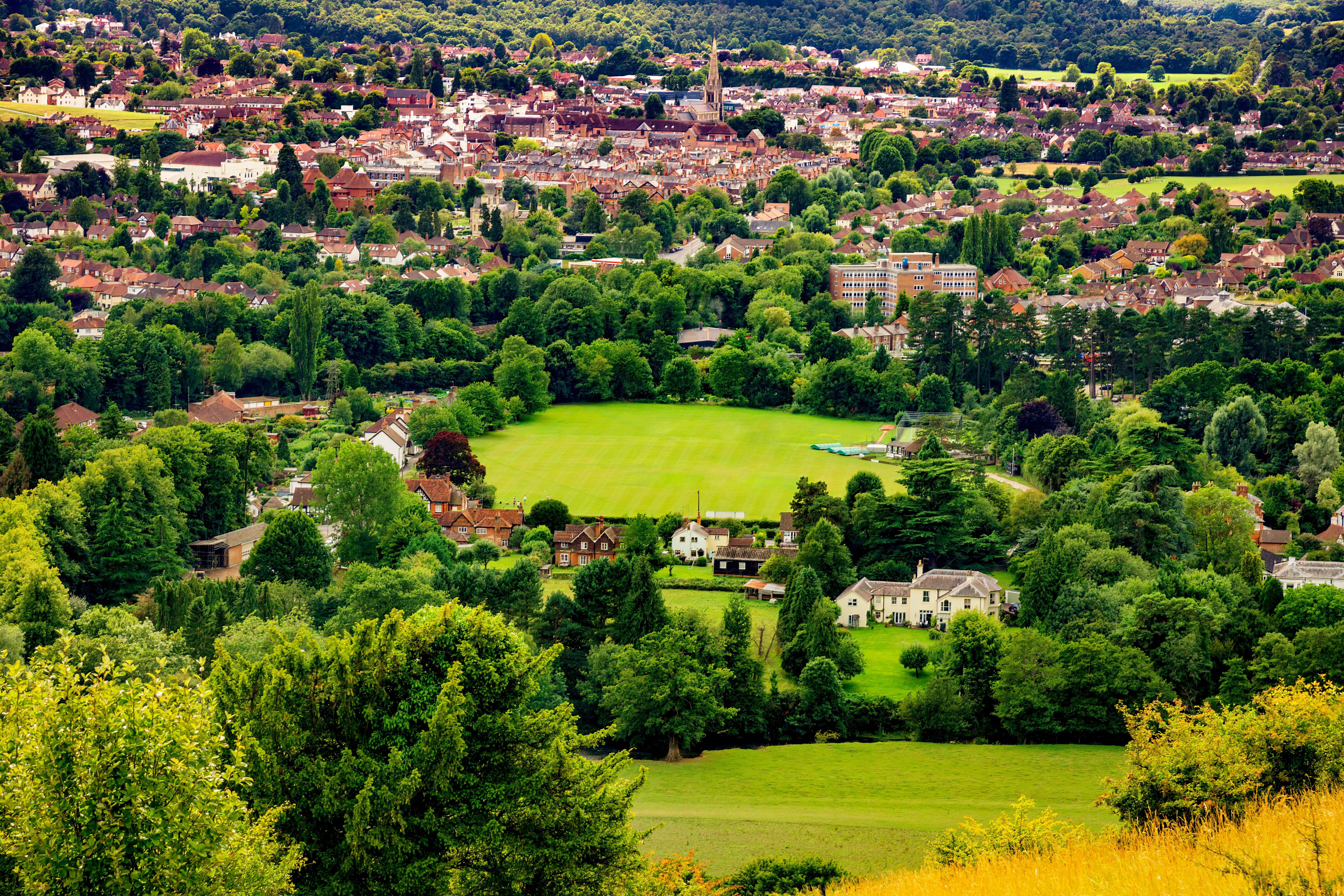 A town with a prominent church spire, surrounded by lush greenery and residential areas.