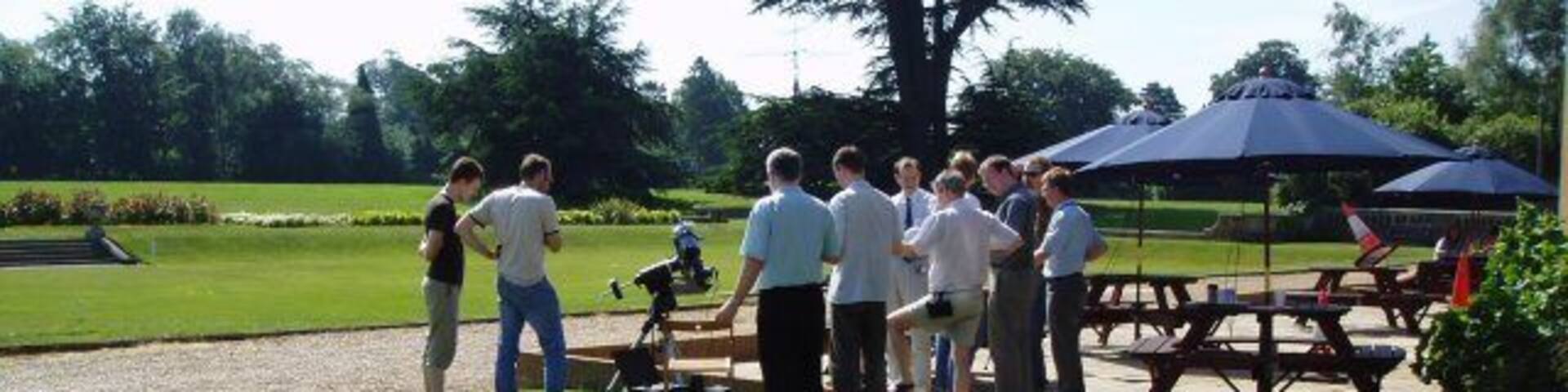 Transit of Venus A group of engineers and scientists gather early in the morning before (possibly) more mundane real work starts, to observe the first transit of Venus across the sun's disc in living memory. The telescope in the picture provided stunning pictures of the entire sequence using digital photography and also through the eyepiece - the actual photos taken can be observed at http://www.jim-easterbrook.me.uk/astro/ap/photo/venus/transit/ Others (including myself, equipped with a pair of binoculars to project the sun's image onto a card) had brought alternative ways of viewing the transit too - but the most innovative "viewing device" can also be seen in the picture - observe the traffic cone experiencing a new purpose as a pinhole camera to the right of the picture! It worked too!