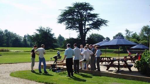 Transit of Venus A group of engineers and scientists gather early in the morning before (possibly) more mundane real work starts, to observe the first transit of Venus across the sun's disc in living memory. The telescope in the picture provided stunning pictures of the entire sequence using digital photography and also through the eyepiece - the actual photos taken can be observed at http://www.jim-easterbrook.me.uk/astro/ap/photo/venus/transit/ Others (including myself, equipped with a pair of binoculars to project the sun's image onto a card) had brought alternative ways of viewing the transit too - but the most innovative "viewing device" can also be seen in the picture - observe the traffic cone experiencing a new purpose as a pinhole camera to the right of the picture! It worked too!