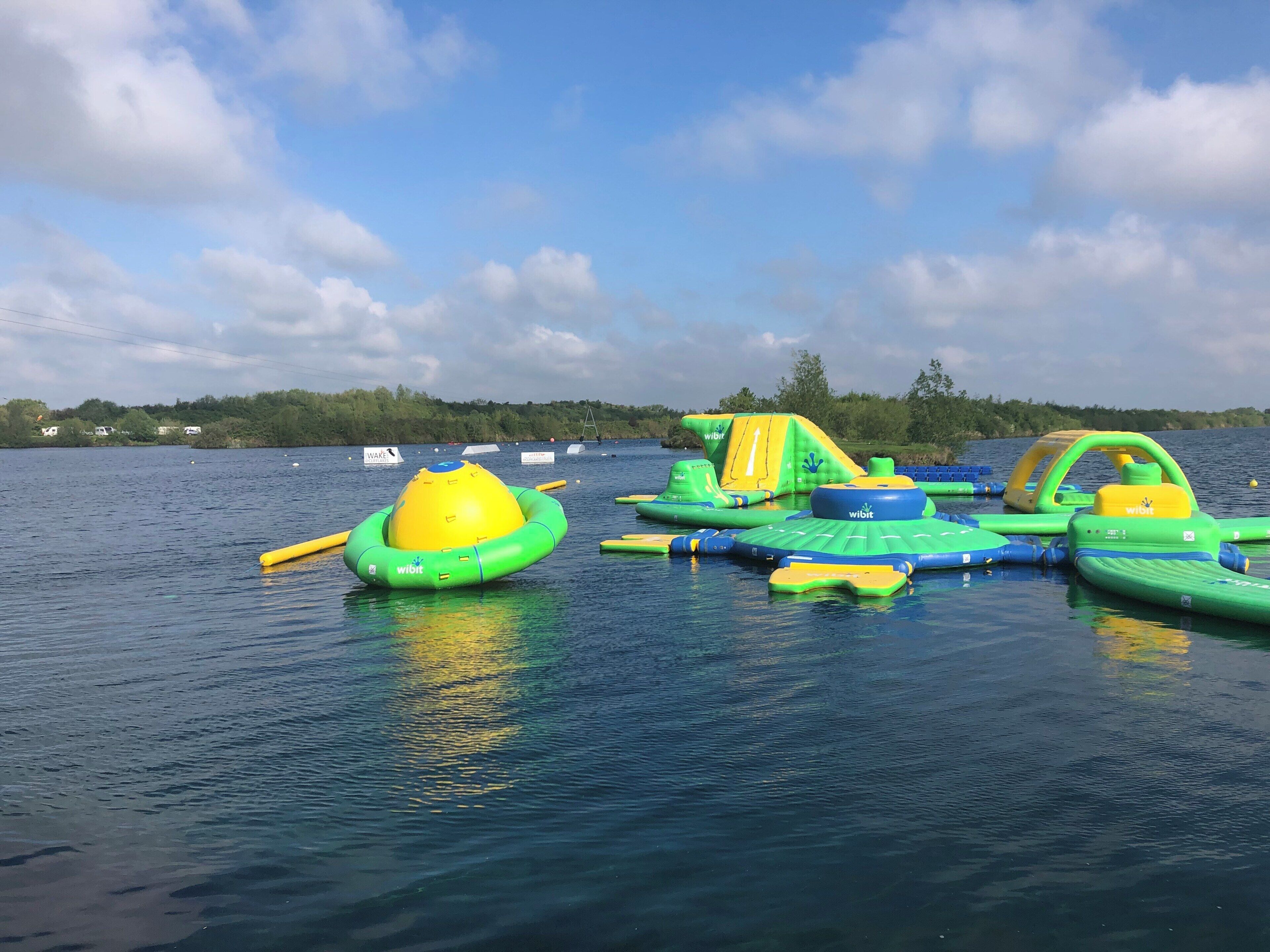 Inflatable water toys on a lake with a forested shoreline.