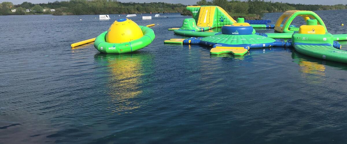 Inflatable water toys on a lake with a forested shoreline.