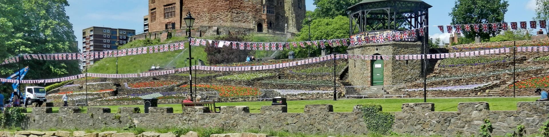 A castle, a gazebo, and a stone wall with a pond in the foreground.