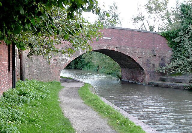 A brick bridge over a narrow canal with a path beside it.